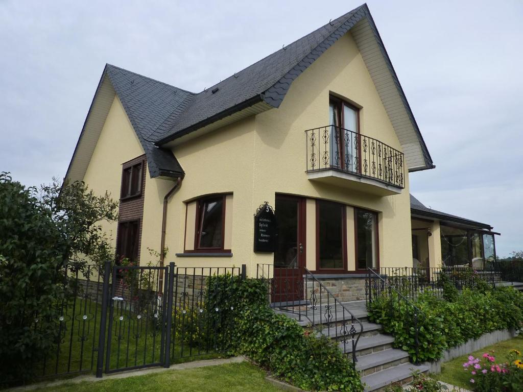 Gästehaus Sylvie في Weywertz: منزل أصفر بسقف أسود