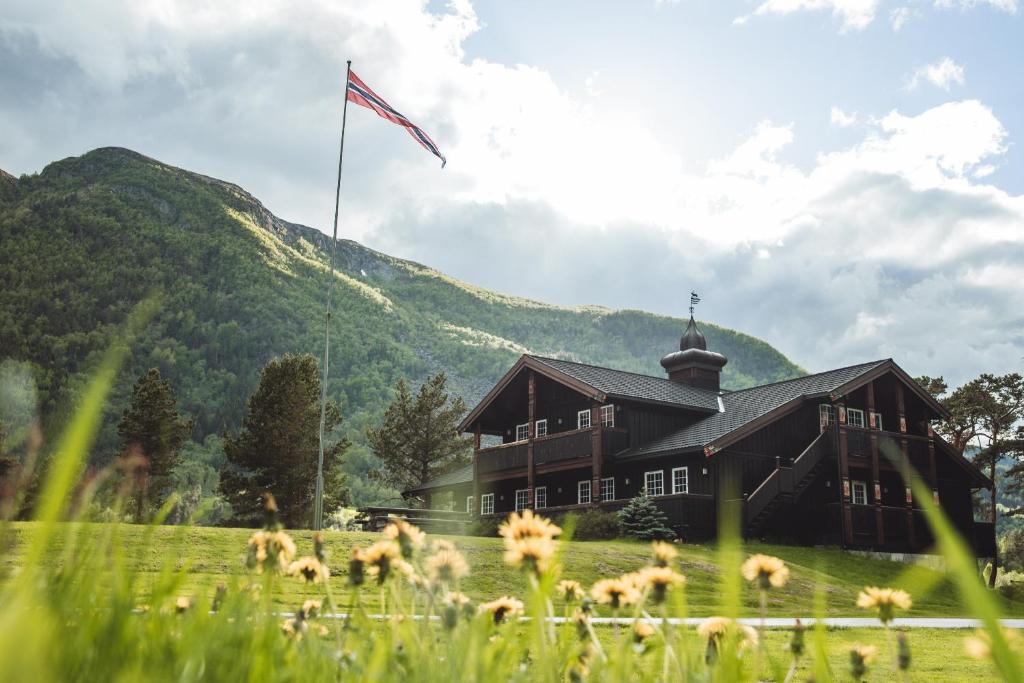 a building with a flag in a field with flowers at Toftemo Turiststasjon in Dovre