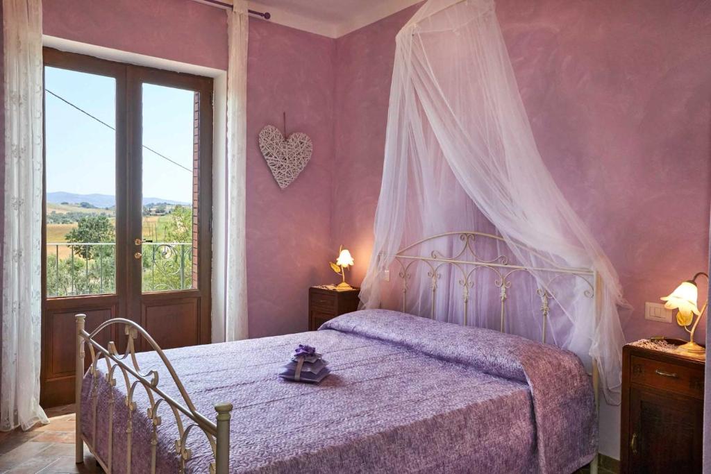 um quarto com uma cama de dossel e uma janela em Agriturismo MonteCrespini em Saturnia
