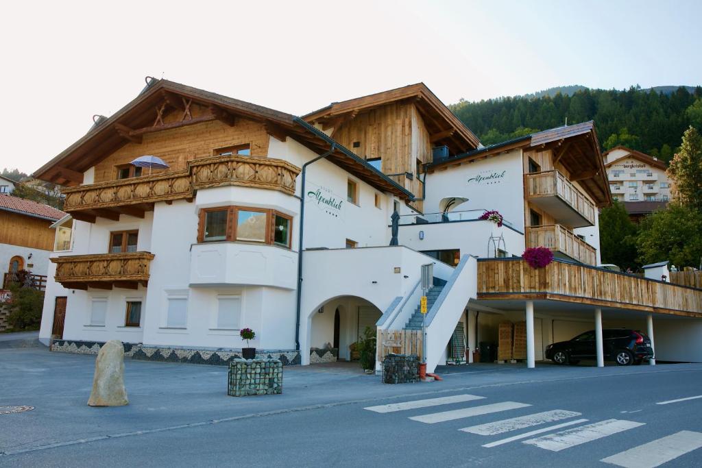 um grande edifício branco com varandas de madeira ao lado de uma rua em Haus Alpenblick em Ladis