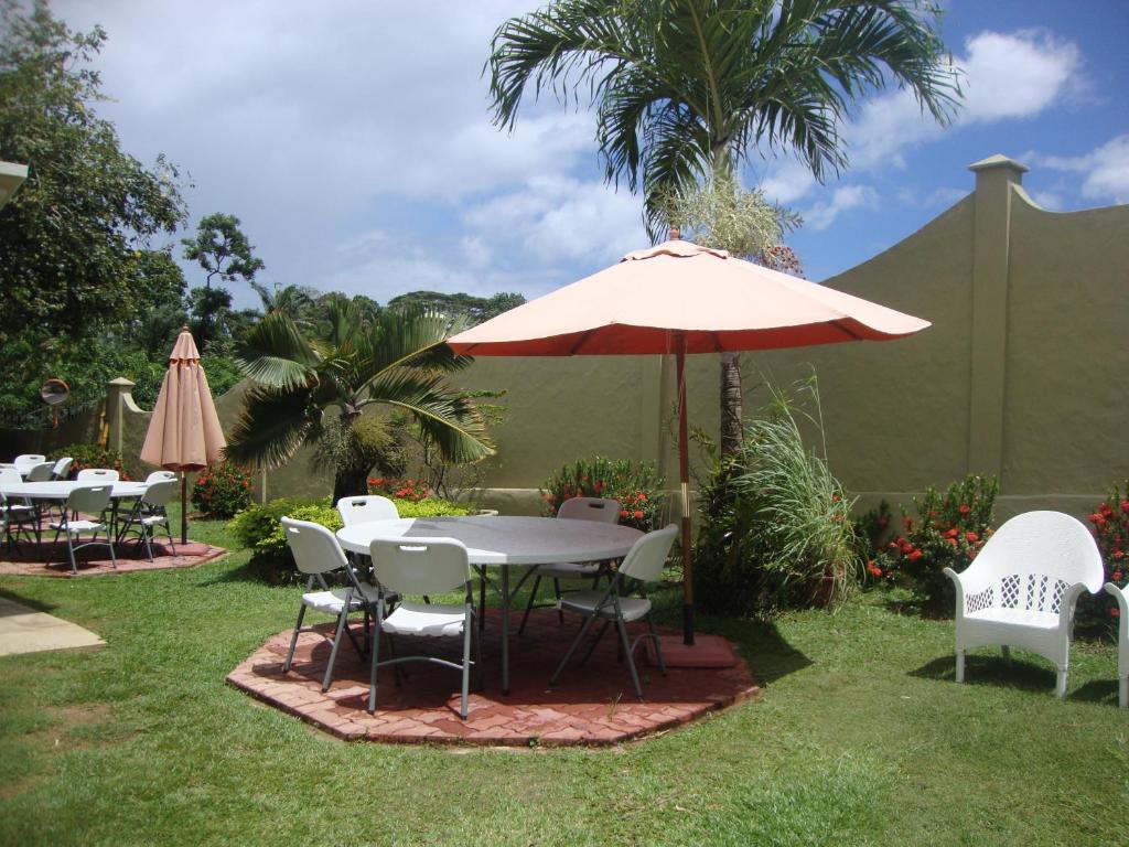 une table, des chaises et un parasol dans l'herbe dans l'établissement Bel Air Hotel, à Victoria