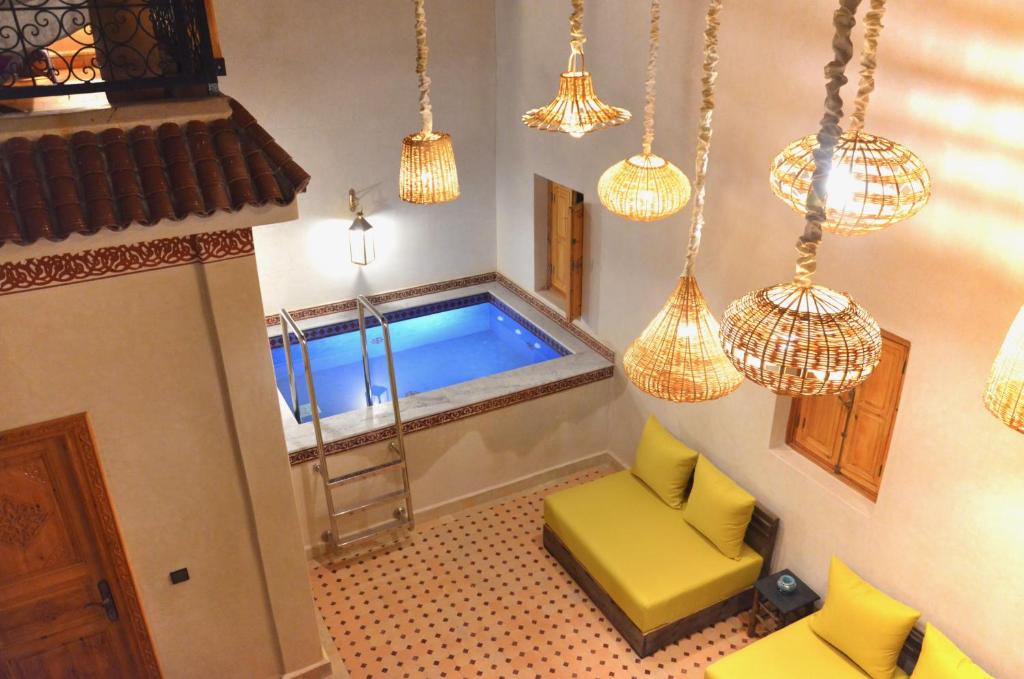 a room with a swimming pool with chandeliers at Riad azra Marrakech in Marrakesh