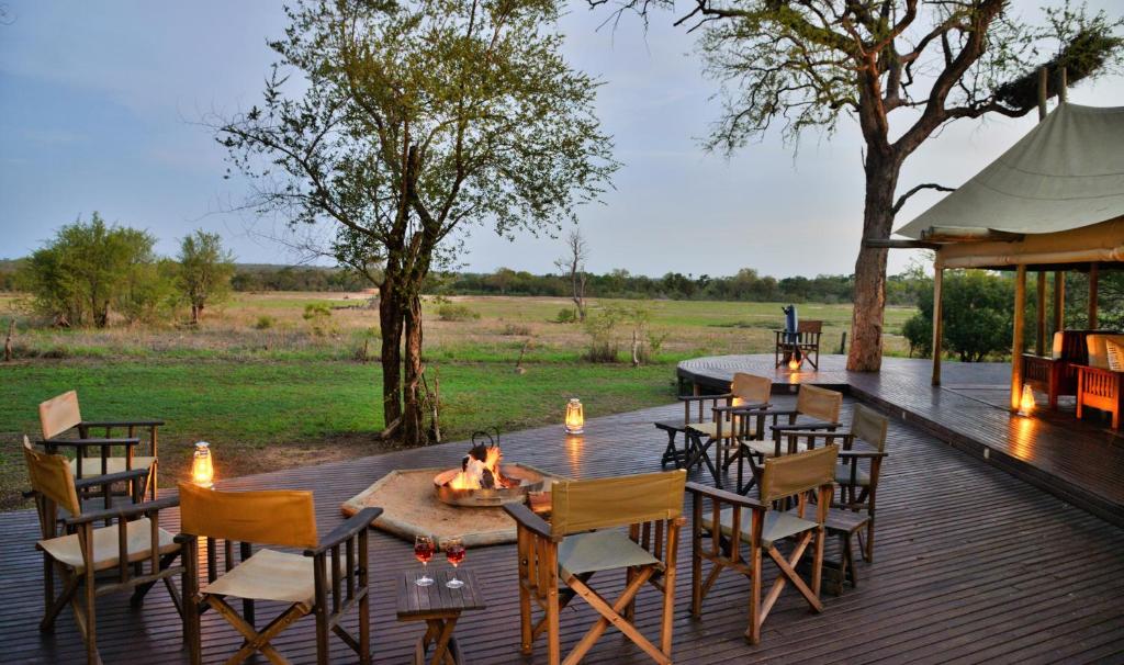 una terraza de madera con mesa y sillas. en Rhino Walking Safaris en Skukuza