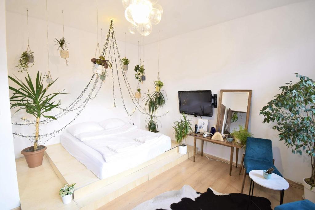 a bedroom with a white bed and potted plants at Apartament na modrzejowskiej pełen sztuki i zieleni in Sosnowiec