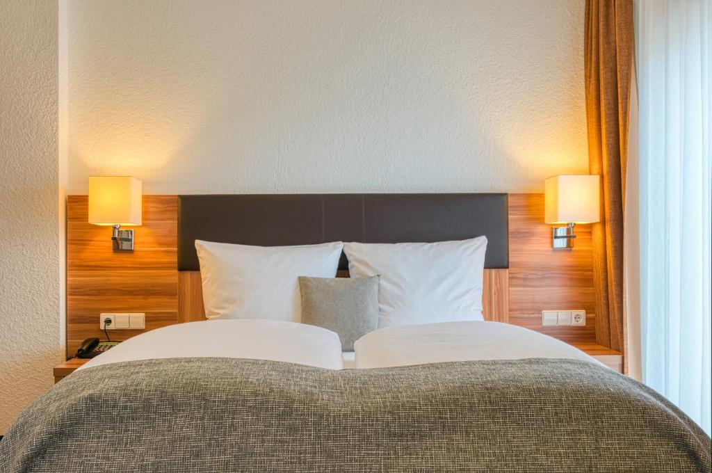 a bedroom with a large bed with two lamps at Centro Hotel Sautter in Stuttgart