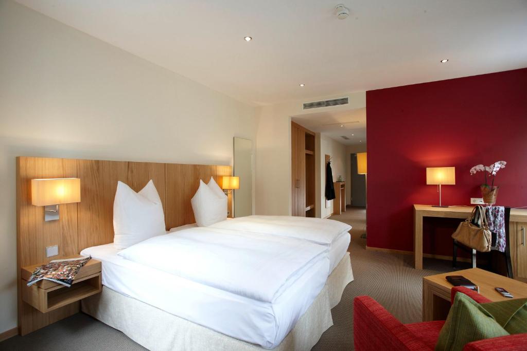 uma grande cama branca num quarto com uma parede vermelha em Hotel Falken em Memmingen