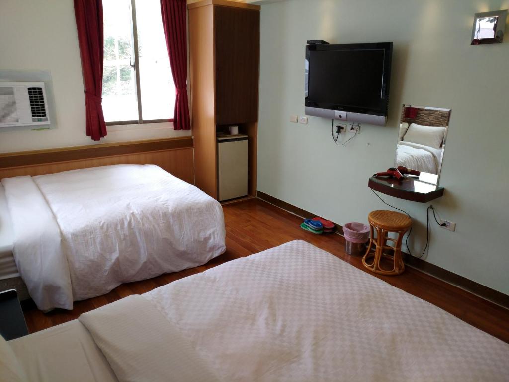 a hotel room with a bed and a flat screen tv at Hong Ben Hotel in Kenting