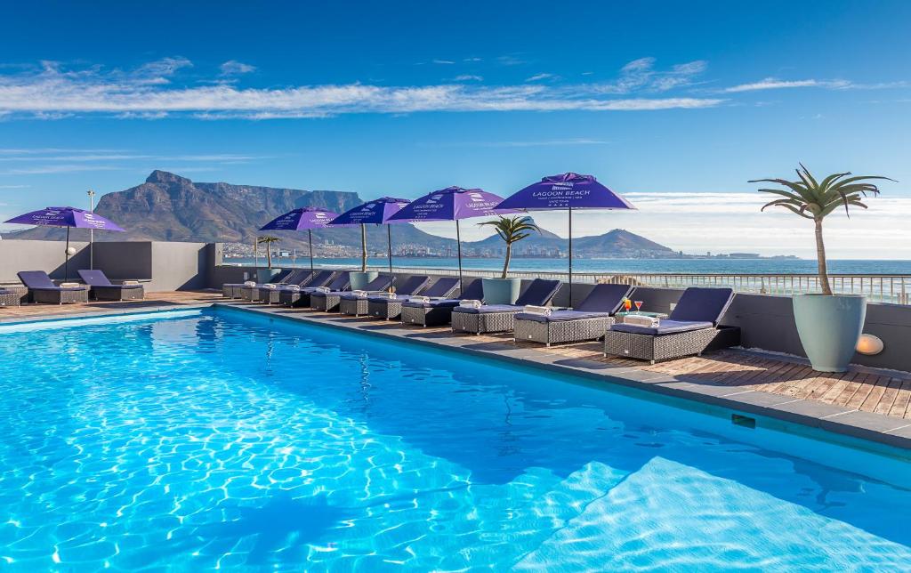 een zwembad met stoelen en parasols op een gebouw bij Lagoon Beach Hotel & Spa in Kaapstad