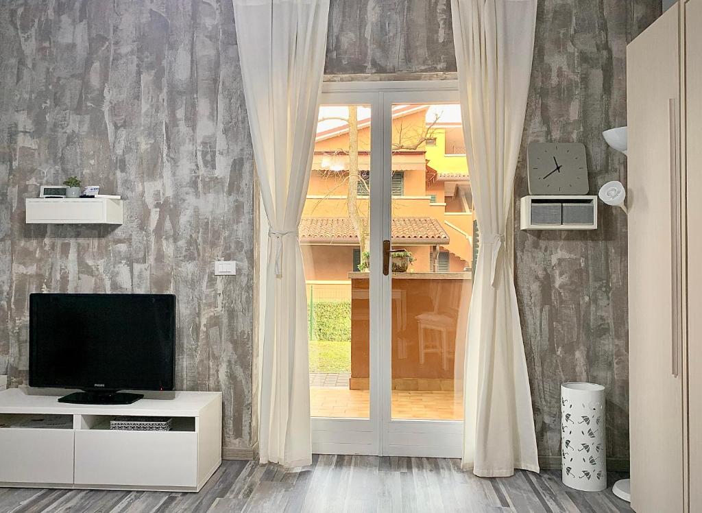 a living room with a television and a window at Azur Apartment Sirmione in Sirmione
