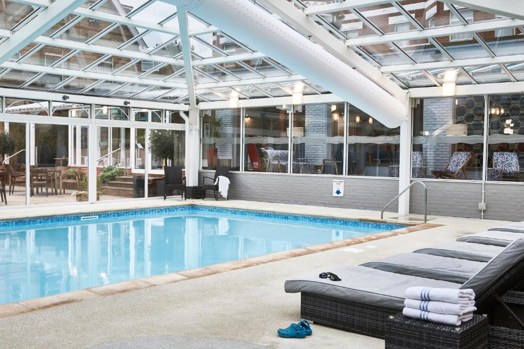 - une piscine avec des chaises longues dans un bâtiment dans l'établissement Bournemouth West Cliff Hotel, à Bournemouth