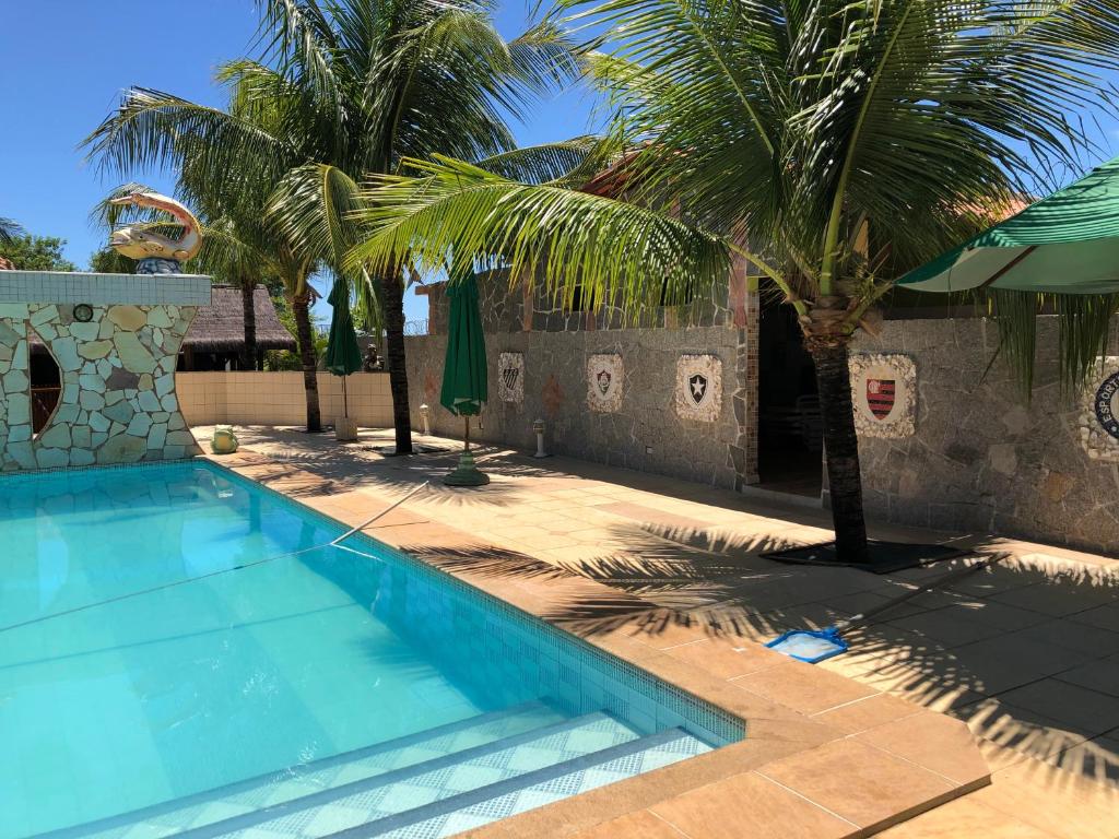 a swimming pool with palm trees next to a building at Pousada Capyvara in Arenápolis