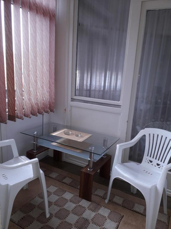 uma mesa de vidro e duas cadeiras brancas num quarto em Apartments Lela em Bihać