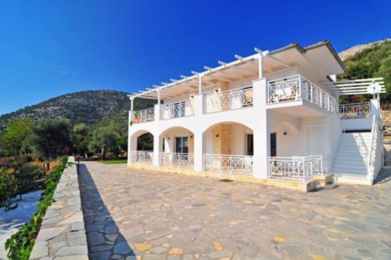 a large white house with a balcony on a stone driveway at Villa Diana in Áyios Yeóryios