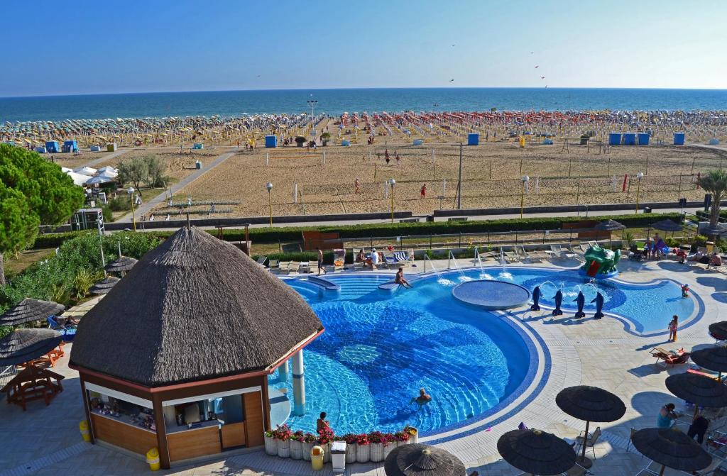 a swimming pool at a resort with a beach at Ashanti Aparthotel Wellness&Spa in Bibione