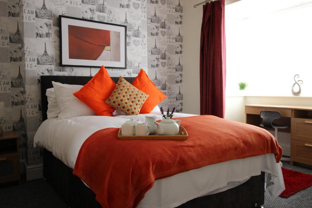 a bedroom with a large bed with orange pillows at Spacious House in Cleethorpes - sleeps 10 in Cleethorpes