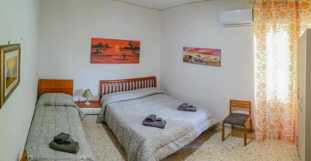 um quarto com 2 camas, uma cadeira e uma janela em Metro Guest House em Nápoles
