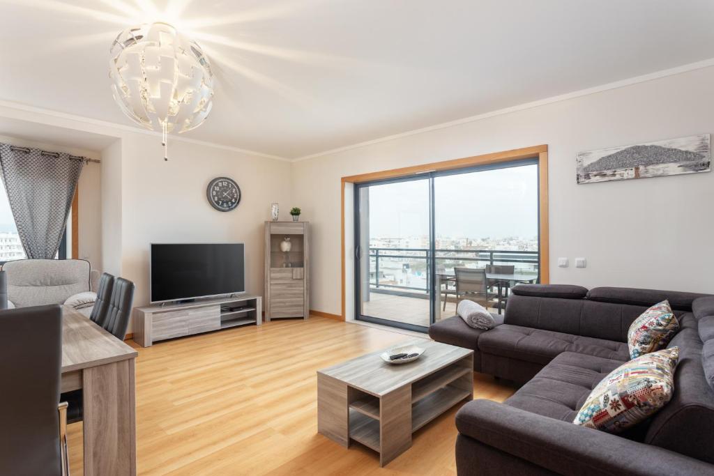 a living room with a couch and a tv at Privilege Apartment Galichet with Rooftop Pool, Village Marina - Olhão in Olhão