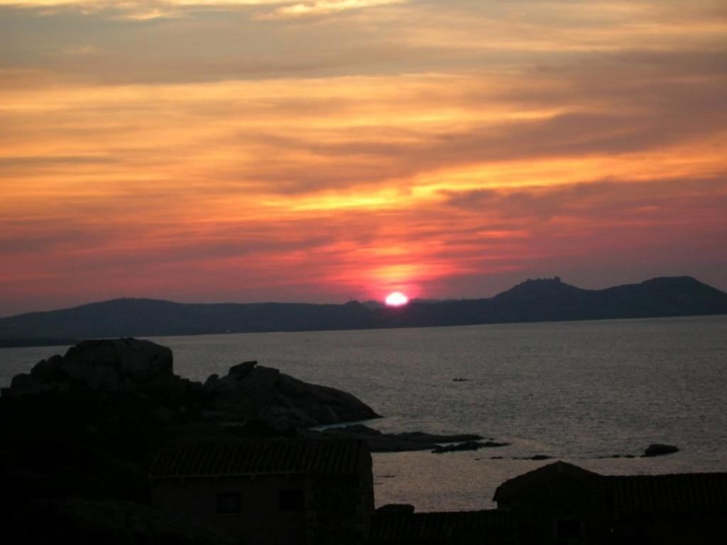 een zonsondergang boven het water met de zon in de lucht bij Cormorani Alti in Baja Sardinia