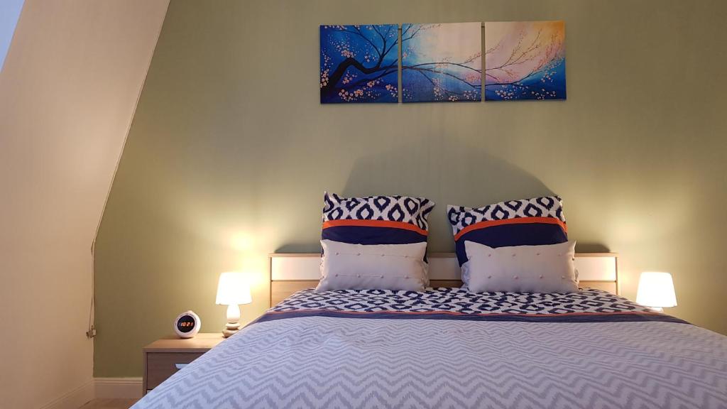 ein Bett mit zwei Kissen und einem Gemälde an der Wand in der Unterkunft Gite D'Elnon-Libre in Saint-Amand-les-Eaux