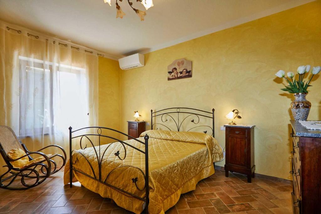 um quarto com uma cama, uma cadeira e uma janela em Agriturismo MonteCrespini em Saturnia