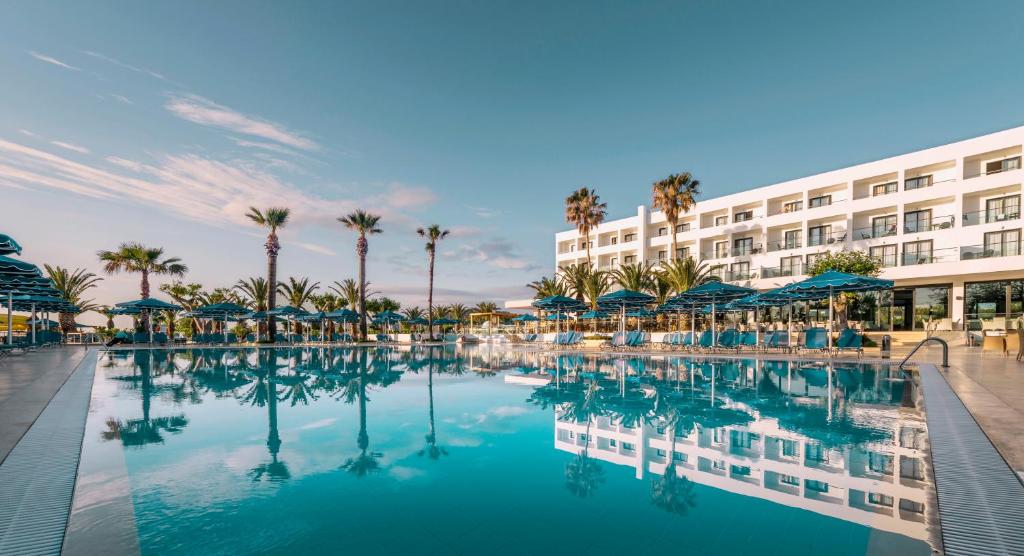 een zwembad in een resort met palmbomen en een gebouw bij Mitsis Faliraki in Faliraki
