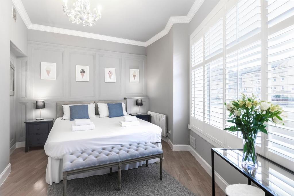 a white bedroom with a large bed with blue pillows at Ice Cream Suite in Edinburgh