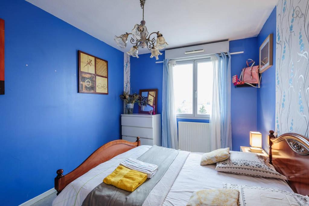 - une chambre avec des murs bleus et un lit avec des oreillers jaunes dans l'établissement COSY ROOM CROIX ROUSSE, à Lyon