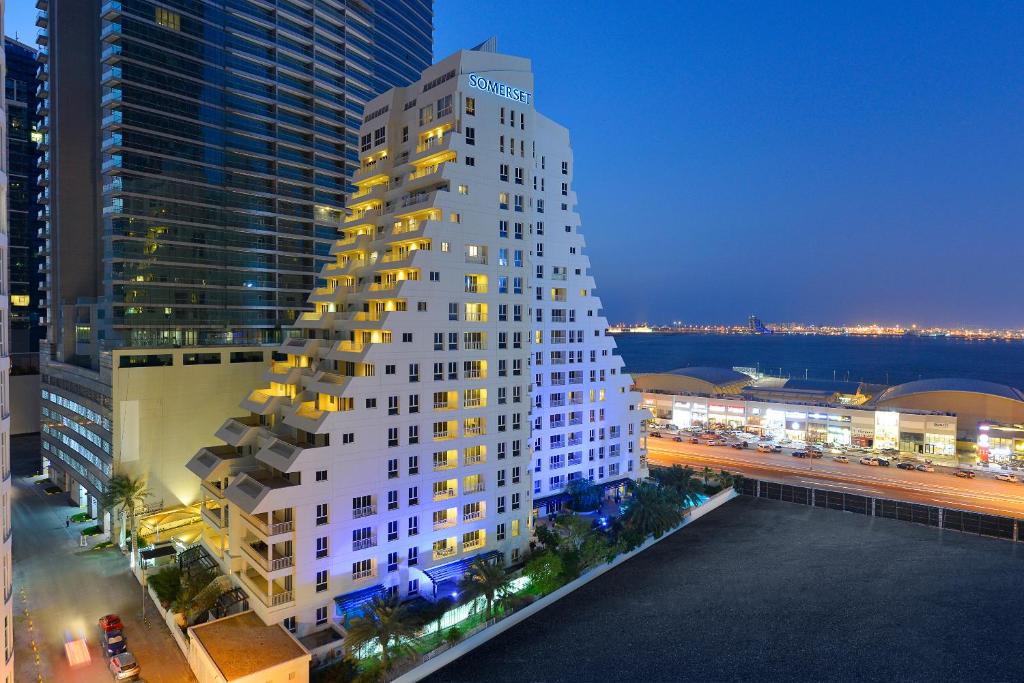 a tall white building in a city at night at Somerset Al Fateh Bahrain in Manama