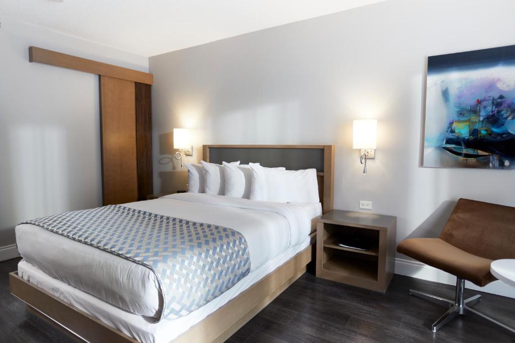a hotel room with a large bed and a chair at Hôtel Cofortel in Quebec City