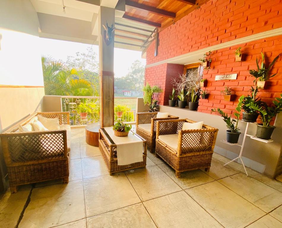 a patio with wicker chairs and tables and a brick wall at Magen in Imphal