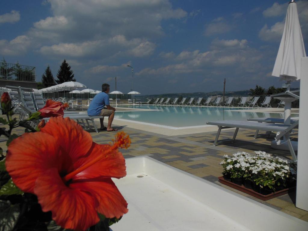 a man sitting on a bench next to a swimming pool at I Perticali in Carrù