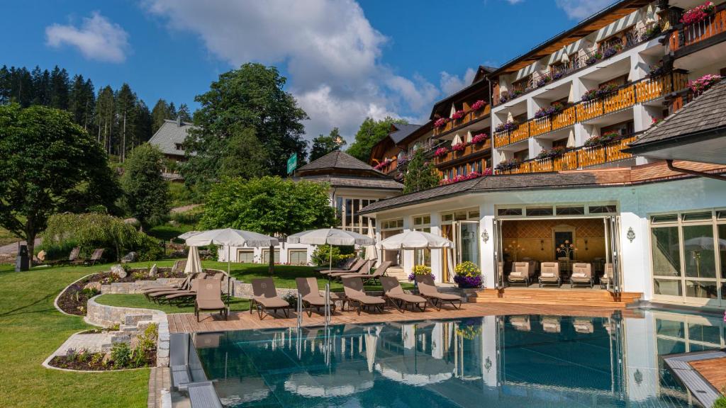 a hotel with a swimming pool in front of a building at Hotel Kesslermühle in Hinterzarten