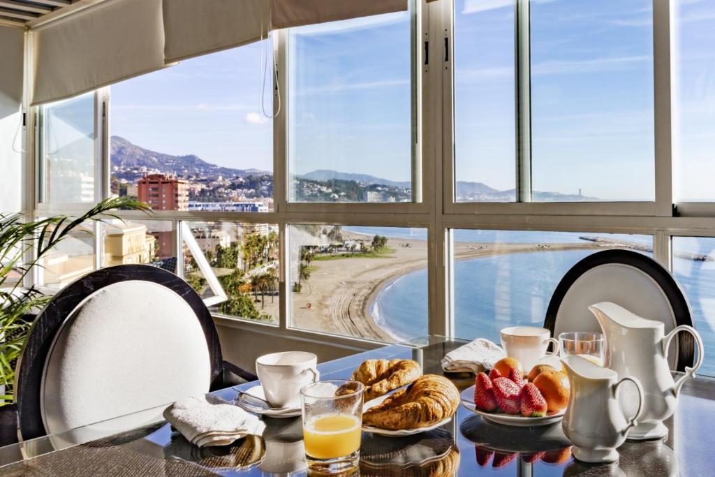 einen Tisch mit Frühstückszutaten und Meerblick in der Unterkunft Frente a playa Malagueta Miramar in Málaga