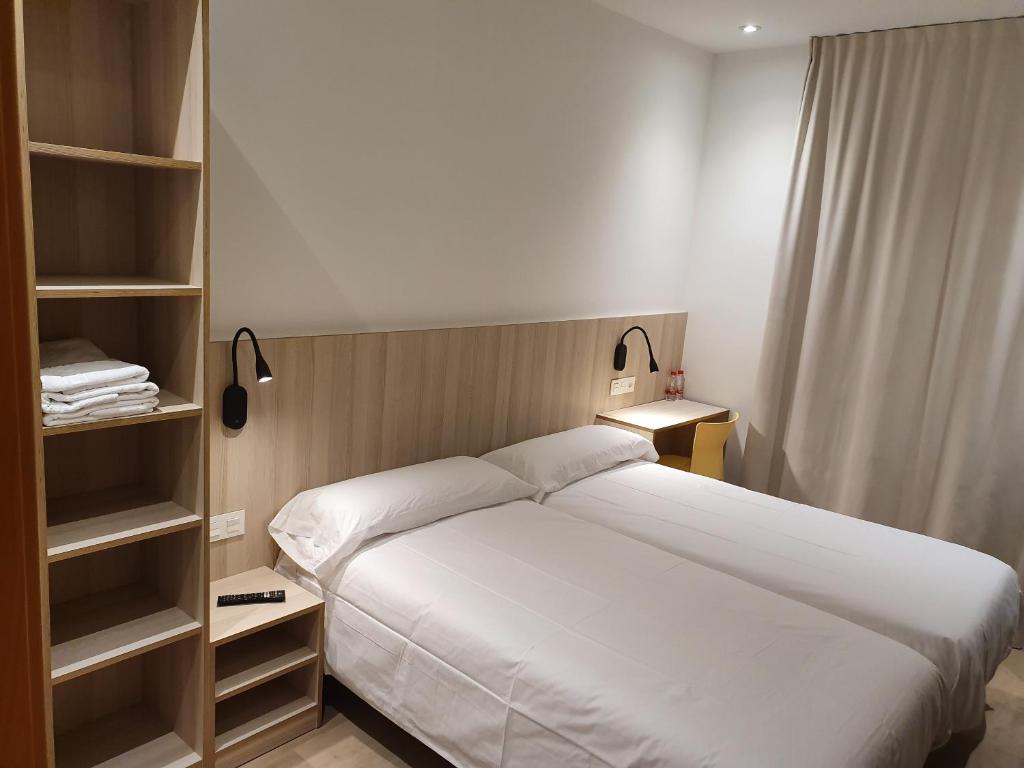 a bedroom with a large white bed and shelves at Hostal Conde Güell in Barcelona