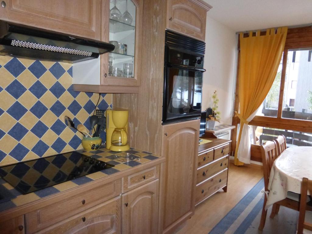 een keuken met houten kasten en een fornuis met oven bij CREPUSCULE 11 in Le Sauze
