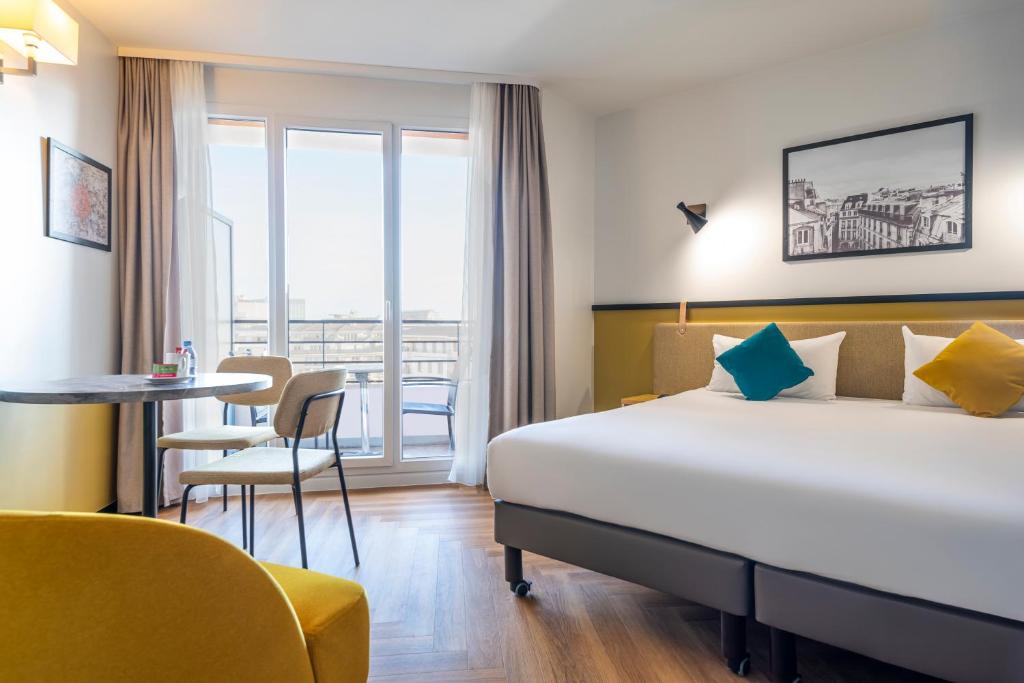 une chambre d'hôtel avec un lit, une table et des chaises dans l'établissement Aparthotel Adagio Paris Montrouge, à Montrouge