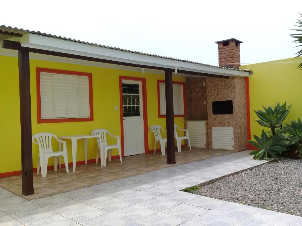 a yellow house with a table and chairs at Pousada Cabral in São Gabriel