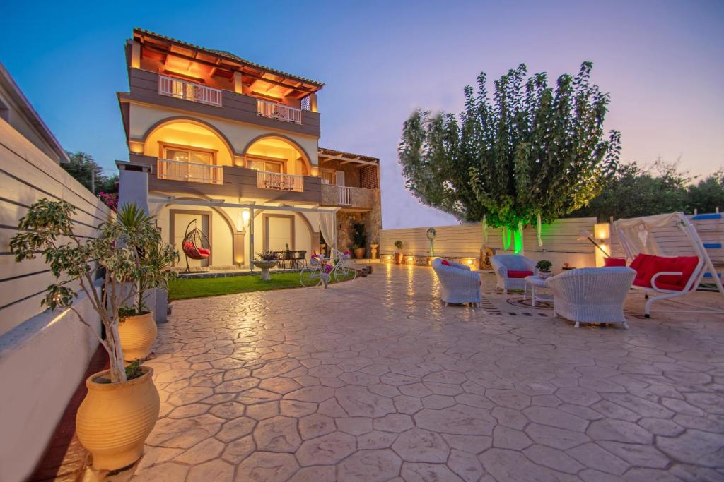 Casa D'Oro Exclusive Villa في Kypseli: منزل به فناء وكراسي بيضاء ومبنى