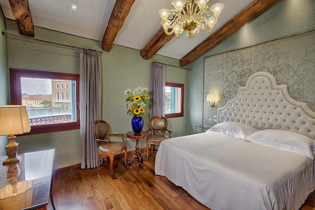 a bedroom with a white bed and a vase of flowers at Hotel Santa Chiara in Venice