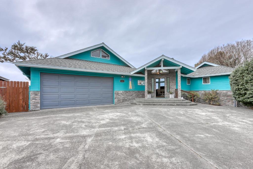 ein blaues Haus mit einer Einfahrt davor in der Unterkunft Mermaid Cove in McKinleyville