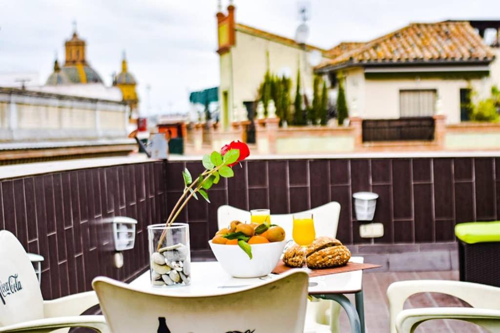 a table with a bowl of fruit and a vase with a flower at Ático céntrico plaza Moravia ,San Julian. in Seville