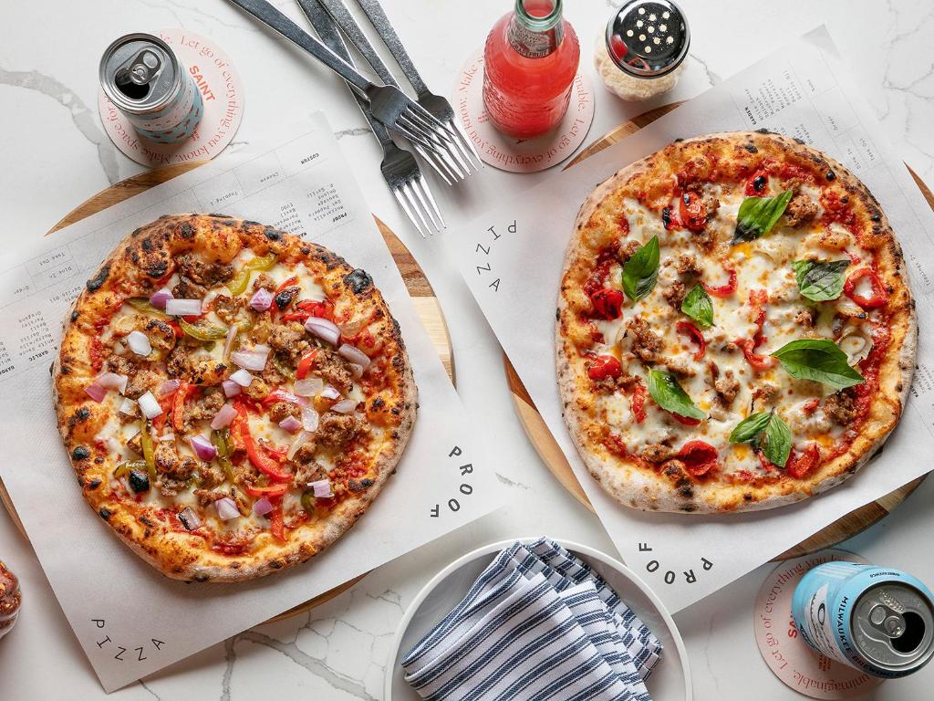 two pizzas sitting on top of a table at Saint Kate - The Arts Hotel in Milwaukee