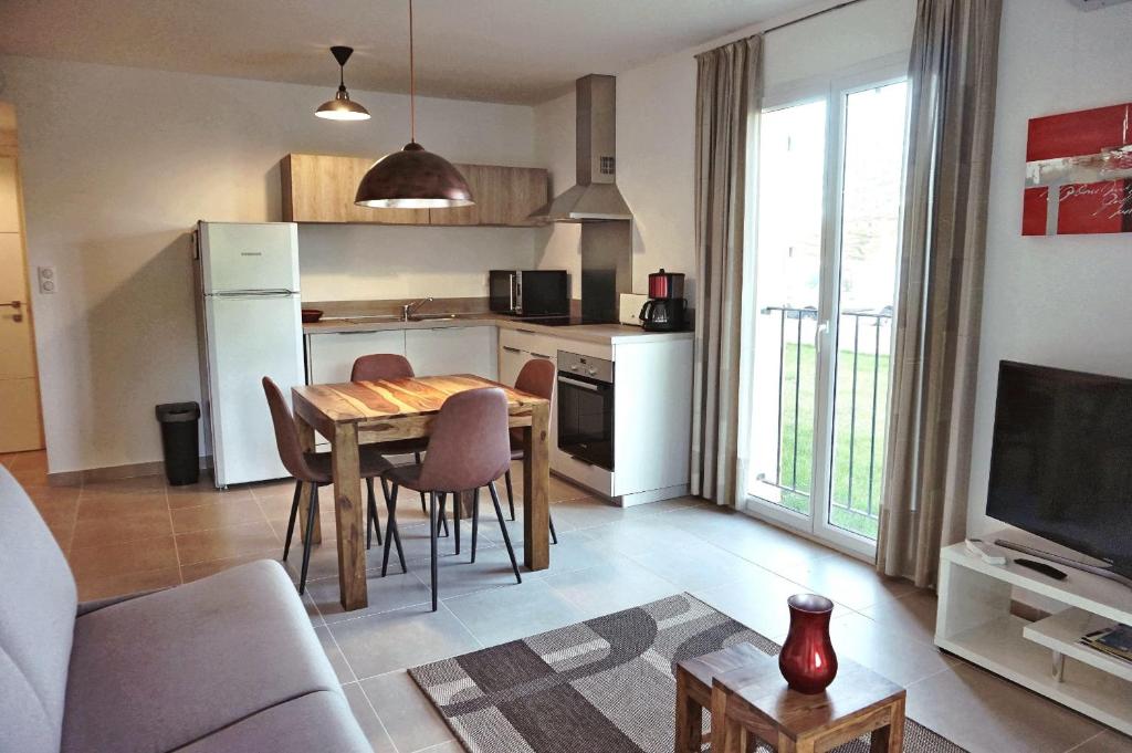 Una cocina y una sala de estar con mesa y sillas. en Domaine A Mortella T2, en Saint-Florent