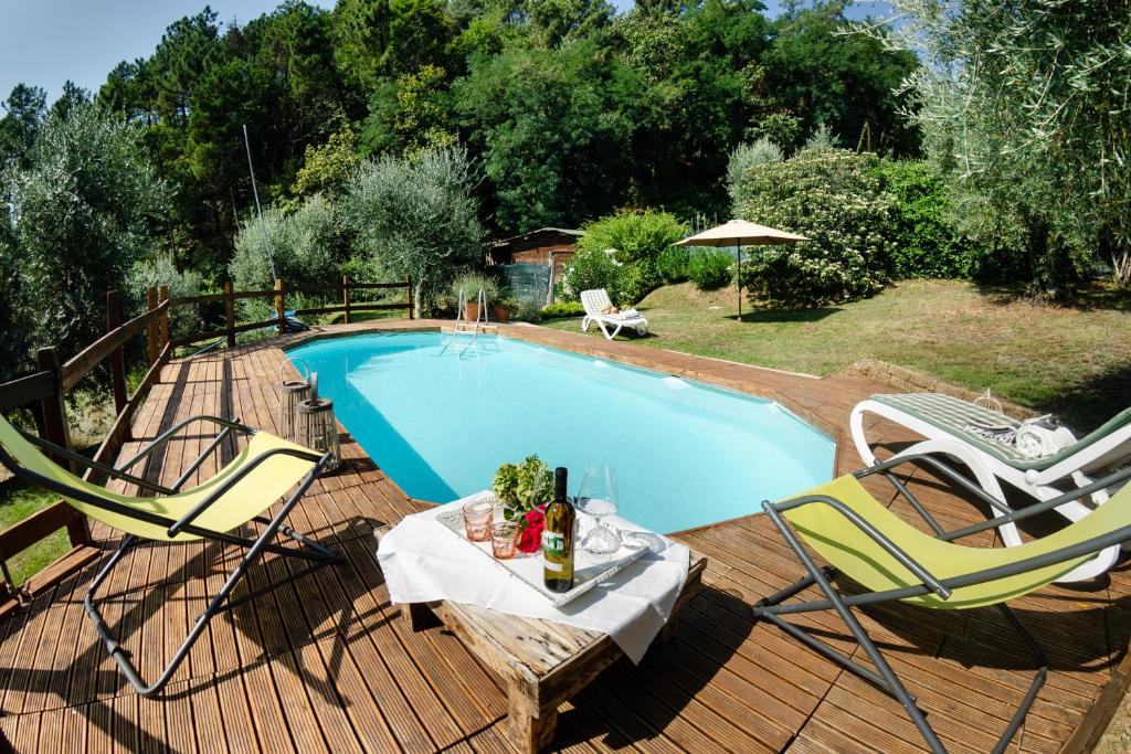 a swimming pool with two chairs and a table with a bottle of wine at Podere L'Istrice in Massa e Cozzile