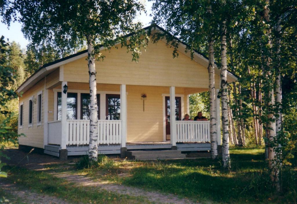 a small house with a porch in the woods at Koskelon Lomamökit in Rääkkylä