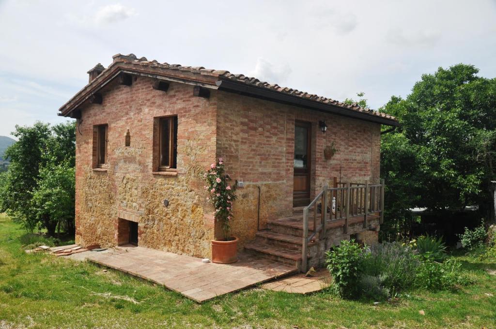 ein kleines Backsteinhaus mit einer Veranda und einer Treppe in der Unterkunft Agriturismo Colombino in Siena