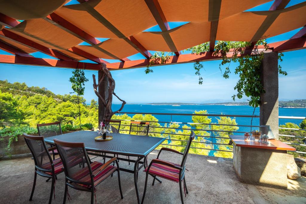 einen Tisch und Stühle auf einer Terrasse mit Blick auf das Wasser in der Unterkunft Holiday home Maslinova in Vela Luka