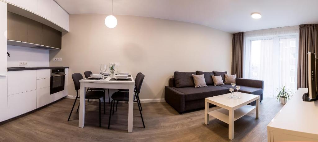 een keuken en een woonkamer met een bank en een tafel bij AM Apartamentai in Klaipėda