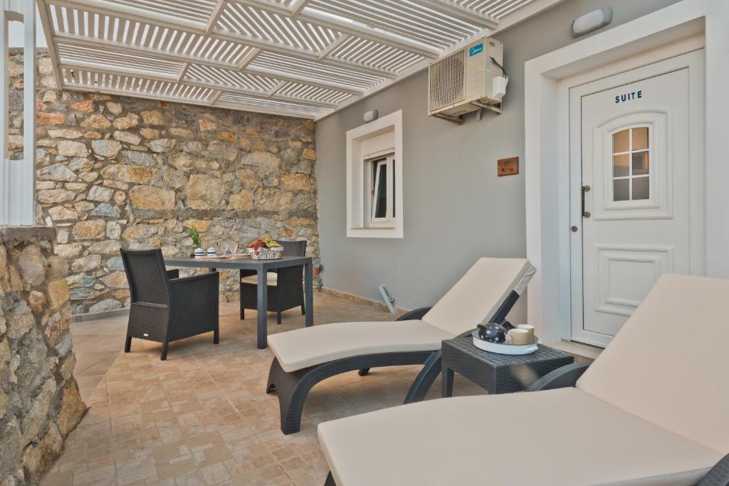 a room with chairs and a table and a stone wall at Kalimera Karpathos Exclusive Villas in Afiartis