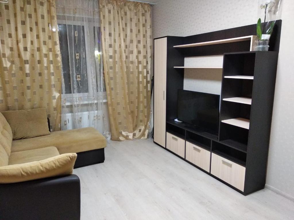 ein Wohnzimmer mit einem TV und einem Sofa in der Unterkunft Уютные апартаменты 1 комн квартира, ЖК Губернский in Krasnodar